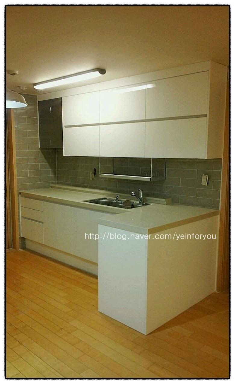 화이트 수납장과 그레이 타일이 조화를 이루는 주방 전경