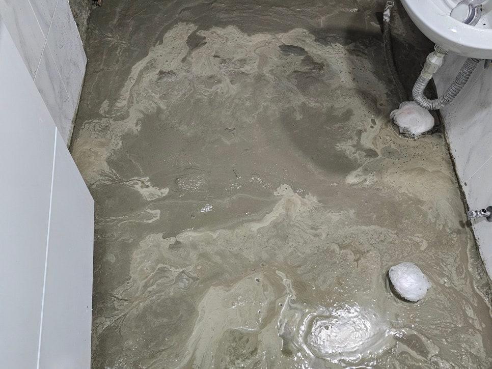 물이 흐르는 바닥과 수도꼭지, 세면대가 있는 욕실