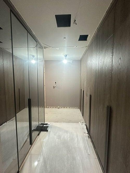 회색 유리 슬라이딩 도어와 우드톤 수납장이 어우러진 복도