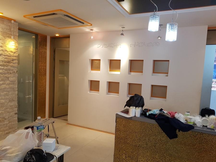 흰 벽과 오렌지 포인트, 금색 카운터가 어우러진 실내 전경