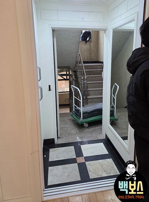 흰 벽과 대비되는 타일 바닥의 현관 모습